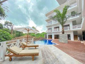 a patio with chairs and an umbrella and a pool at Made Canggu 77 in Canggu
