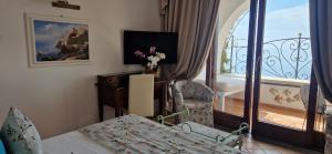 a living room with a bed and a balcony at Albergo La Conca Azzurra in Conca dei Marini