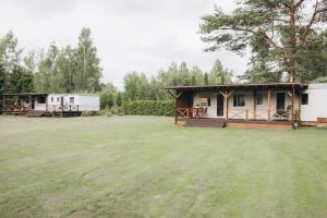 a house with a large grass field in front of it at Atvases in Pērkone
