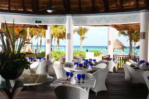 プラヤ・デル・カルメンにあるサンドス カラコル エコ リゾート オール インクルーシブの白い椅子とテーブル、海を望むレストラン