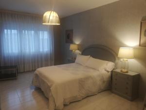 a bedroom with a bed with white sheets and two lamps at Areos in A Pobra do Caramiñal