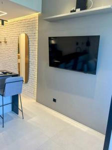 Habitación con TV en la pared y silla azul. en Beachfront Studio,, en Río de Janeiro