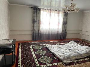 a bedroom with a bed on a rug and a window at magic home in Boz-Beshik