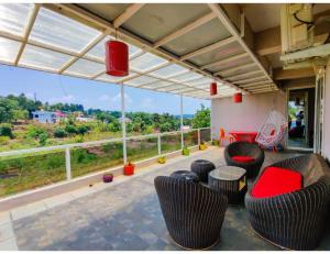 a patio with chairs and tables and a large window at Dream Valley Resort and Farmhouse, Mahableshwar in Mahabaleshwar