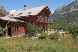 una casa in legno in un campo con montagne sullo sfondo di Chalet cadre montagne au pied des Ecrins a Saint-Martin-de-Queyrières