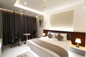 Un dormitorio con una cama y una mesa y sillas. en Hotel Lémore Stay & Dine, en Solapur