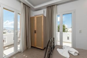 a bedroom with a bed and a balcony with windows at Penelope Apartments C in Vívlos +18 photos
