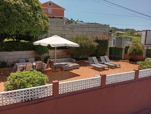 eine Terrasse mit einem Sonnenschirm, Stühlen und Tischen in der Unterkunft Espectaculares vistas a la Ría de Aldán in Bueu