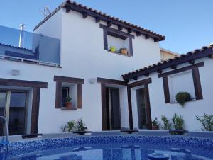 a white house with a swimming pool in front of it at La BUHARDILLA DE CHARLIN in Casas de Ves