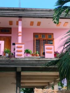 a pink house with potted plants on the balcony at Sarojinilaya Homestay in Guwahati