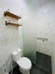 a bathroom with a toilet and a glass shower at Lulu's Guest House in Purwokerto +10 photos
