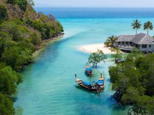 three boats in the water next to a beach at SAii Phi Phi Island Village in Phi Phi Islands