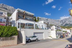 a white house with a car parked in front of it at Exlusive Villa M -Baska Voda in Baška Voda