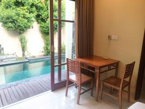 a table and chairs next to a window with a pool at Dana Villa Bali in Seminyak
