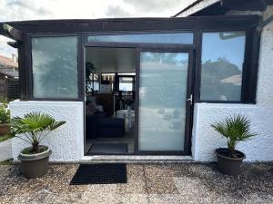 a glass door of a house with two potted plants at Logement agréable sur Le Teich in Le Teich