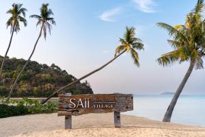 a sign on a beach with two palm trees at SAii Phi Phi Island Village in Phi Phi Islands