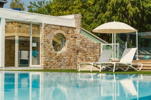a pair of chairs and an umbrella next to a swimming pool at La Maison des Bois in Bagnoles de l'Orne
