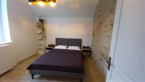 Un dormitorio con una cama y una pared de ladrillo. en Gîte L'Instant Présent, en Messeix