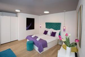 a bedroom with a bed with purple and white pillows at Pansion Kamenar 2 in Primošten