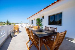 a patio with a wooden table and chairs on a balcony at UFitness Retreat Guesthouse in Vila Real de Santo António
