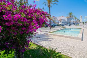a park with purple flowers next to a swimming pool at UFitness Retreat Guesthouse in Vila Real de Santo António