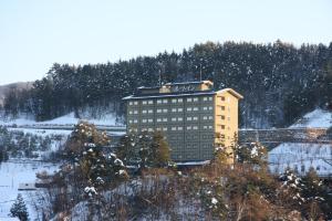 a building with a sign on top of it in the snow at Route Inn Grantia Hidatakayama in Takayama