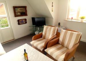 un salon avec deux chaises et une télévision dans l'établissement Haus am Schlei Noor, à Maasholm