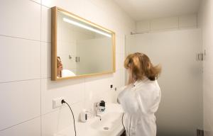 a woman standing in front of a sink in a bathroom at Duinhotel Tien Torens in Zoutelande