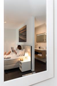 a woman laying on a bed reading a book at Duinhotel Tien Torens in Zoutelande