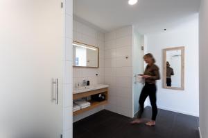 a woman standing in a bathroom with a sink at Duinhotel Tien Torens in Zoutelande