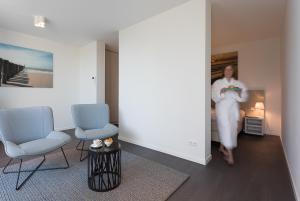 a woman is walking through a room with two chairs at Duinhotel Tien Torens in Zoutelande