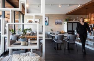 a woman walking through a restaurant with tables and chairs at Duinhotel Tien Torens in Zoutelande