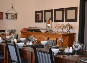 una sala da pranzo con un lungo tavolo in legno e bicchieri da vino di 7 Cities Guesthouse a Cradock