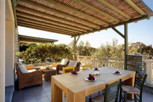 a patio with a wooden pergola and a table and chairs at Aithra -Agios Petros Andros in Gavrio