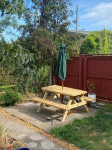 a wooden picnic table with a green umbrella on it at Manor Close in Wrafton