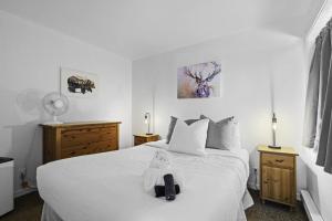 a bedroom with a white bed with a teddy bear on it at Le Skieur in Mont-Tremblant