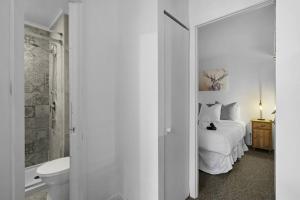 a white bedroom with a bed and a bathroom at Le Skieur in Mont-Tremblant