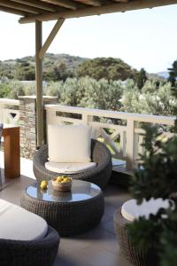 a patio with wicker chairs and a table with a bowl of fruit at Aithra -Agios Petros Andros in Gavrio