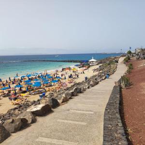 a beach with people laying on the sand and the ocean at Nunoli Duplex Luxury Playa Blanca in Playa Blanca