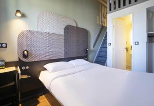 a bedroom with a large white bed and a staircase at B&B HOTEL Avignon 1 in Le Pontet