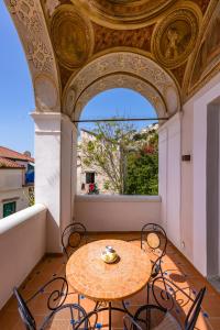 a table and chairs on a balcony with a window at Starhost - ANGOLO FELICE, charming seaview terrace in Vietri sul Mare