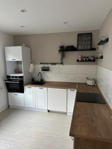 una cucina con mobili bianchi e un piano di lavoro in legno di Ferienwohnung MONI a Penkun