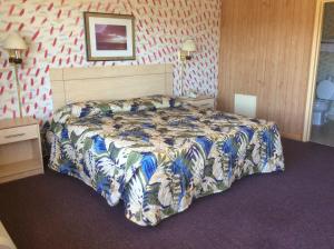 a bedroom with a bed with a comforter on it at MacThrift Motor Inn in Virginia Beach