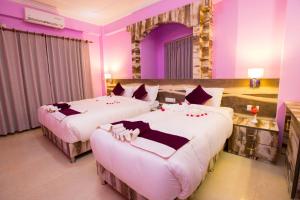 2 letti in una camera d'albergo con pareti viola di Hotel Task International a Pokhara Altre 37 foto