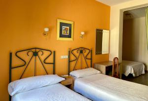 two beds in a room with orange walls at Hostal Fernández Atocha in Madrid +31 photos