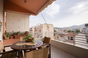 a balcony with a table and chairs and a view at Maria's Airport Apartment, 4' metro, 10' airport, 15' beach, 40' city center in Koropíon
