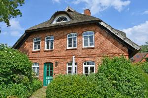 ein rotes Backsteinhaus mit einem Walmdach in der Unterkunft Landhaus am Deich in Middelhagen