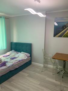 a bedroom with a bed and a table and a painting at Apartamencik Konopnickiej 2 in Dziwnów
