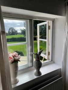 a window sill with a statue of a bunny and flowers at Spenford House 1640 listed house Idilic Location pub walking distance in Shrewsbury