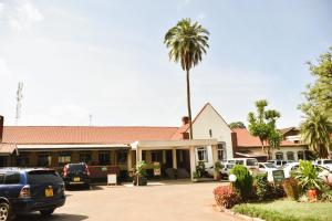 埃尔多雷特Wagon Wheel Hotel Eldoret的停车场前有棕榈树的建筑